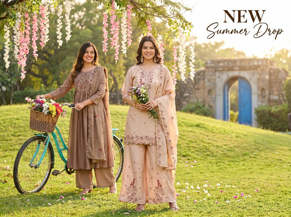 Two women in traditional outfits standing in a garden with flowers and a bicycle, promoting 'New Summer Drop'.