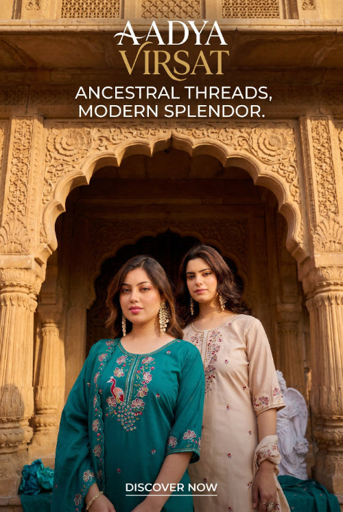 Two women in traditional embroidered dresses standing in front of an ornate architectural background with 'Aadya Virsat' branding.